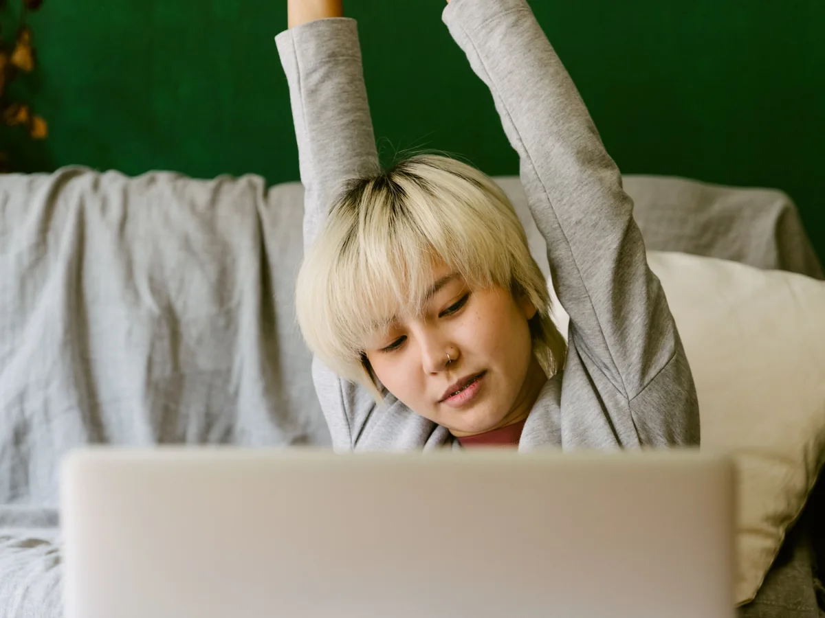 Real photo of a woman stretching her arms during a break from laptop work