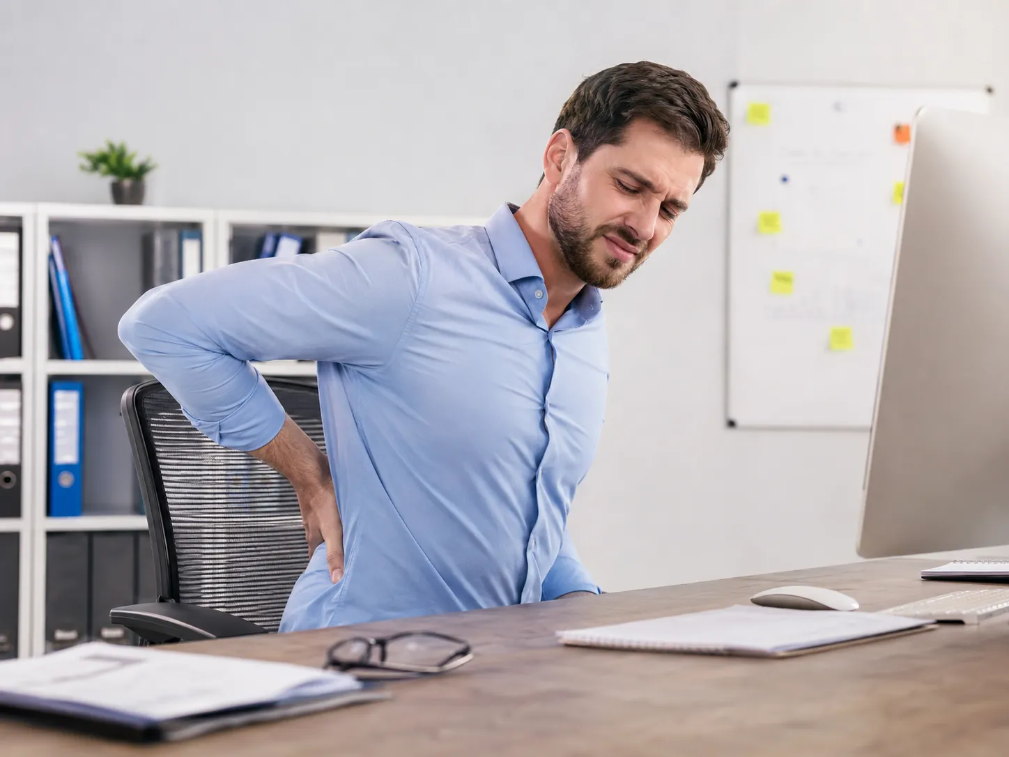 Office worker experiencing lower-back discomfort while seated at a desk
