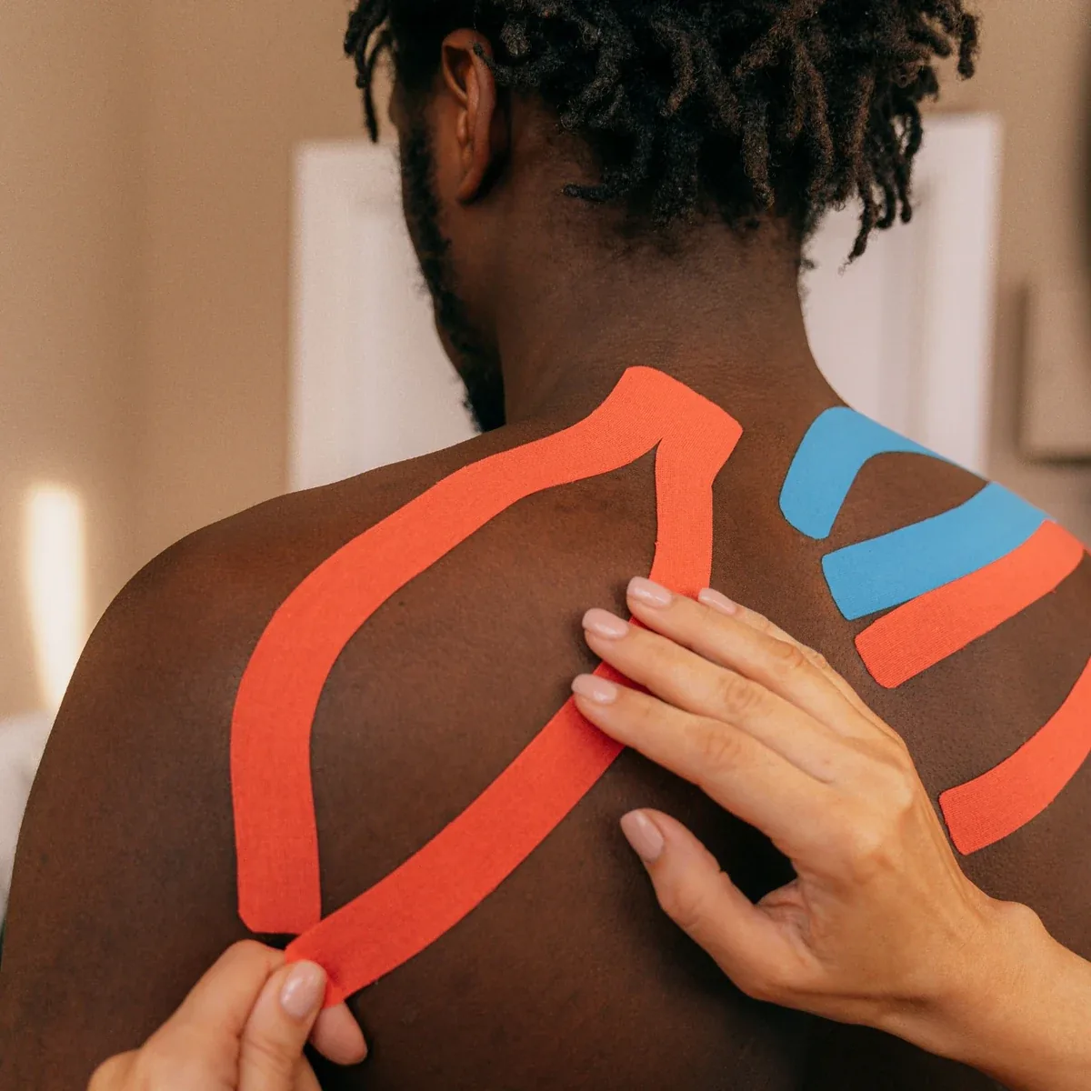 Kinesiology tape being applied to support the shoulder during physiotherapy